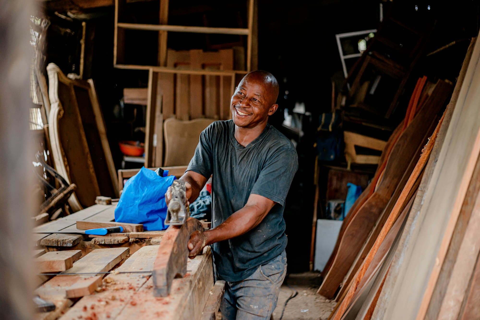 Artisan souriant travaillant le bois dans son atelier